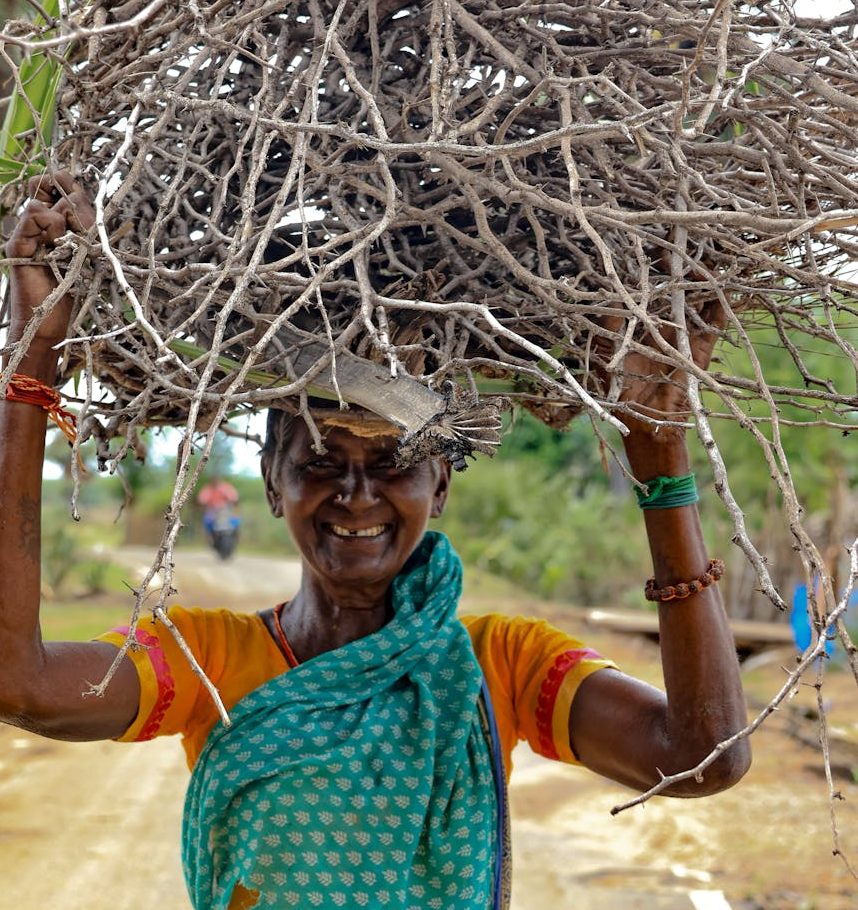 smiling woman carrying firewood in rural setting